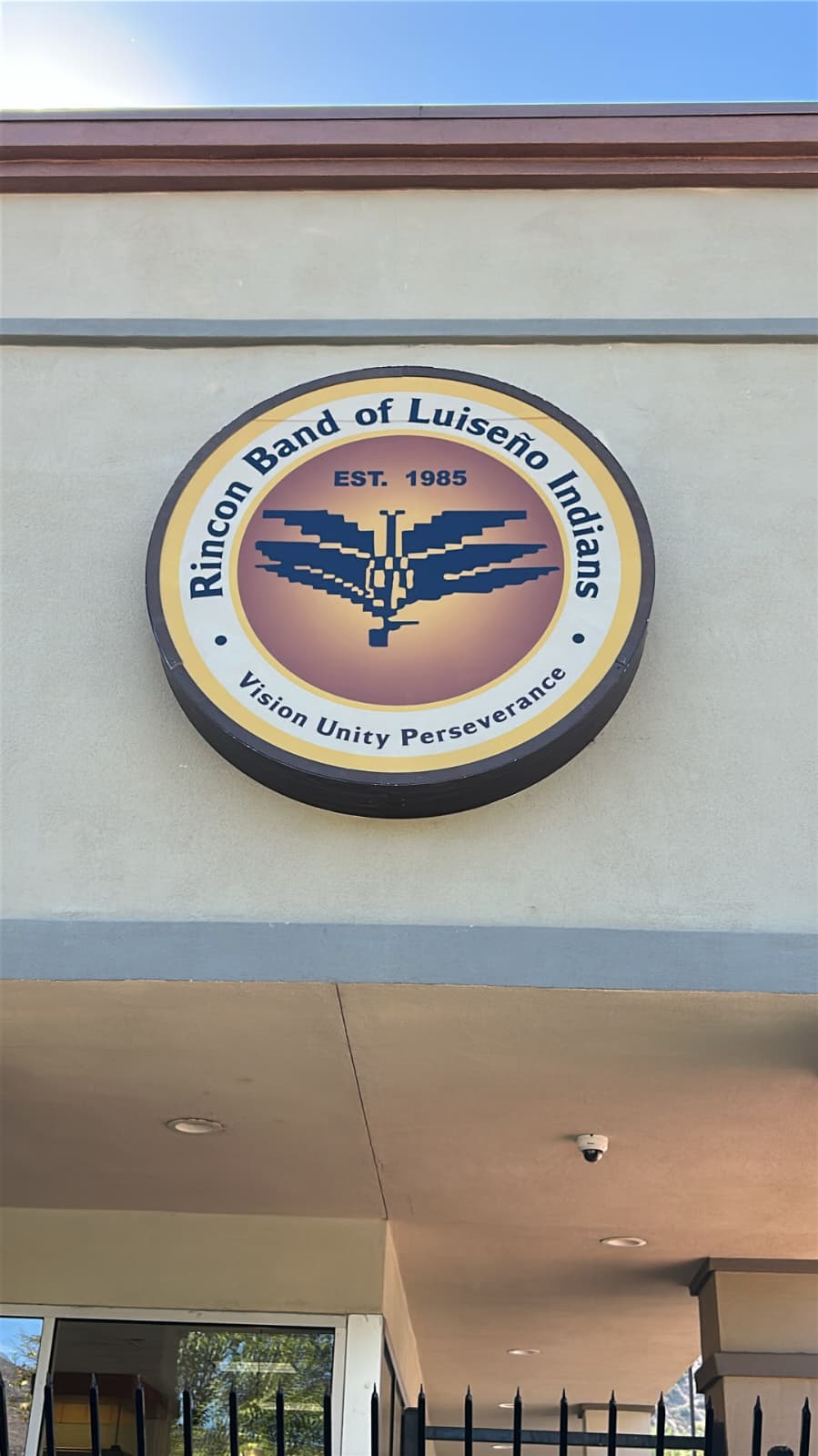 Round exterior logo emblem sign mounted above a building entrance.