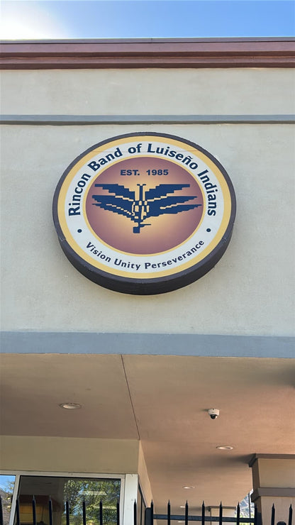 Round exterior logo emblem sign mounted above a building entrance.