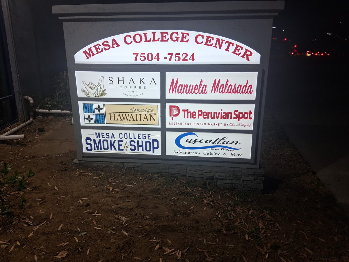 Illuminated multi-tenant monument directory sign photographed at night.