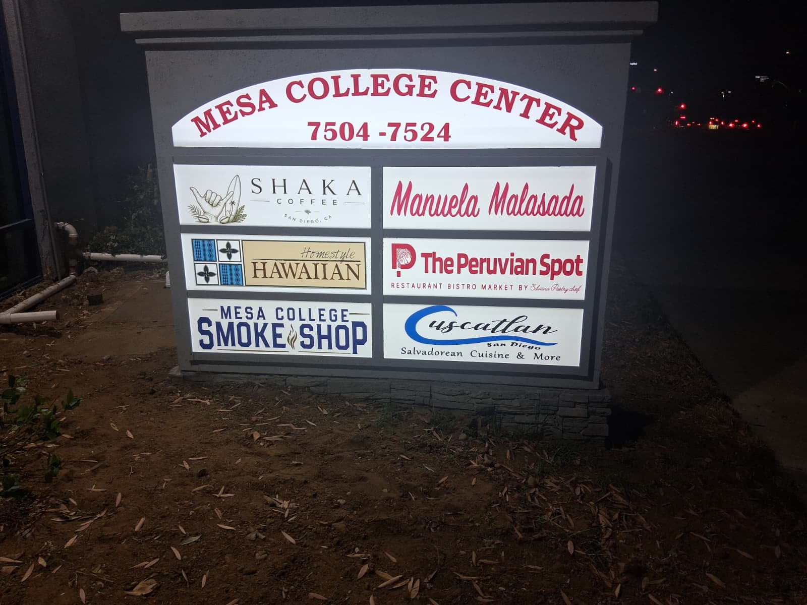 Illuminated multi-tenant monument directory sign photographed at night.