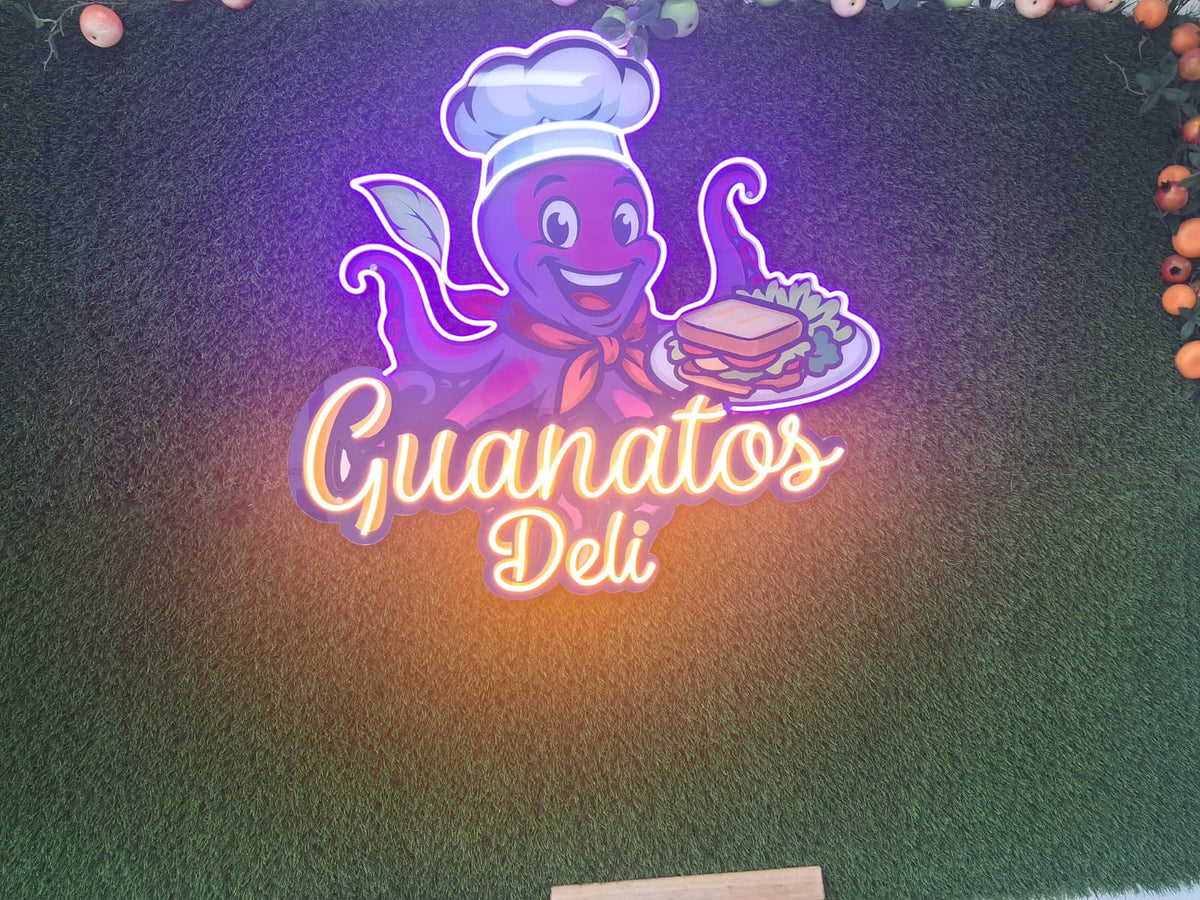 Colorful illuminated custom logo sign mounted on an artificial grass wall.